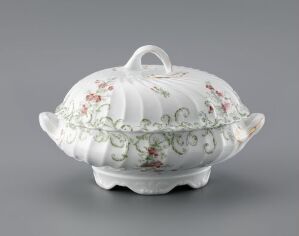  A delicate white feltspar porcelain serving dish with a dome-shaped lid, adorned with hand-colored print decorations of green garland patterns and red-pink floral motifs, featuring gold gilding details. The dish, known as Modell 1111 by an unknown artist, reflects traditional elegance and is designed for dining and serving.