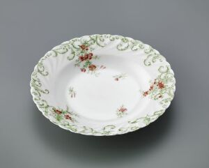  An oval-shaped feldspar porcelain dish with a glossy white base and detailed hand-colored print decorations in pastel green and floral patterns in subdued reds, pinks, and greens, set against a neutral background. Artist name and title are unknown.