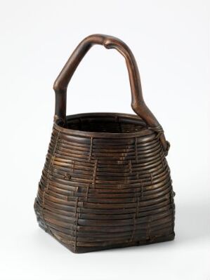  A dark brown woven basket with a sturdy arched handle, featuring a tight and orderly pattern against a neutral background.