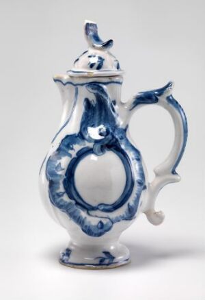  A white-glazed faience pitcher by Herrebøe Fajansefabrikk with hand-painted cobalt blue decorations in a baroque design, featuring a bulbous body, ornate handle and spout, and a decorative lid.