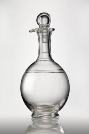  An elegant, clear glass decanter with a rounded body, slender neck, and looped stopper set against a light gray background, showcasing the transparency and reflective qualities of the glass.