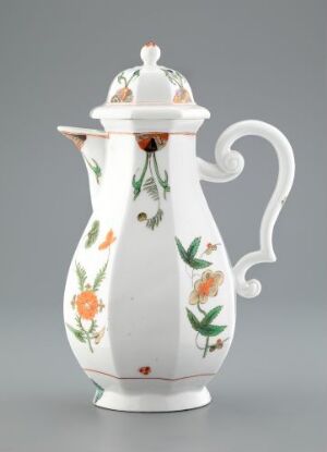  A porcelain coffee pot with a white background decorated with soft green leaves, orange, and peach flowers. The elegant pot has a curvy silhouette with a large, decorative handle and spout, complete with a matching lid.