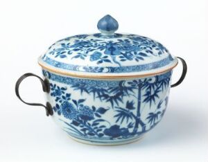  A blue and white porcelain tureen with intricate floral patterns and metallic side handles, with a matching lid featuring a rounded handle on top. Artist name and title unknown.