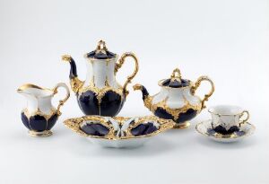  A porcelain tea set with cobalt blue and white design, with gold accents, including a teapot, creamer, sugar bowl, sloped tray, and a cup with saucer, all against a light background.