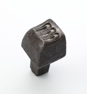  A small, weathered metallic object with a hexagonal base and several parallel grooves on the top, suggesting an industrial tool component with signs of wear and oxidation.