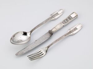  A set of silver-plated tableware consisting of a spoon, fork, and knife designed by Peter Behrens, displaying a cohesive geometric pattern on the handles and resting on a light-gray background.