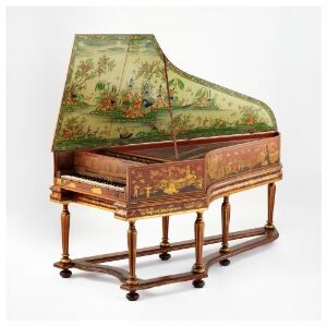  An ornate harpsichord with a painted pastoral scene on the inside lid featuring green countryside and figures in leisurely activities, bordered by rich reddish-brown sides with golden floral patterns, resting on a stand with turned legs and connected by a gold-patterned stretcher.