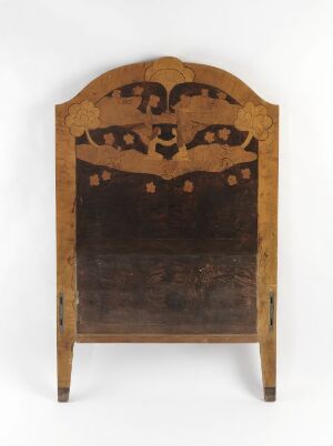  An antique wooden panel with a curved decorative top featuring cut-out patterns, supported by two outward-splayed legs, against a neutral background.