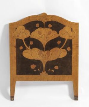 * Antique fire screen with symmetrical dark brown floral inlay designs on a light brown wooden background, featuring an arched top and two short supporting legs at the base.