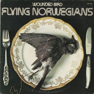  Album cover by Truls Næss og Arne Skiftesvik titled "Wounded Bird-Flying Norwegians," featuring a lifeless bird with spread wings on an ornate plate with a gold rim, flanked by intricately designed silver fork and knife, against a black background.