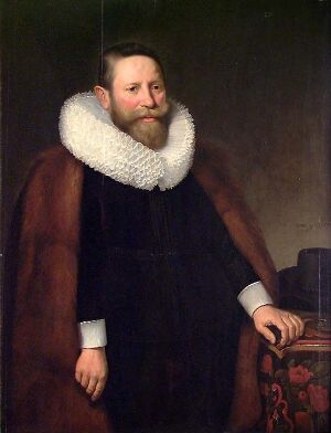  An old master-style portrait of a bearded man with a reddish-brown hair and serious expression, wearing a dark brown cloak and an elaborate white ruff, with his hand resting on a table with a red and gold embroidered cloth. Artist unknown, Dutch.