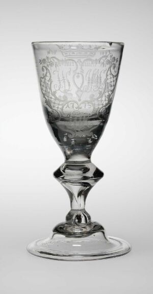  A clear glass goblet with intricate etchings, featuring a broad rim, a tapered bowl with decorative designs, a knob-designed stem, and a wide base, set against a light grey background. Artist name and title are unknown.