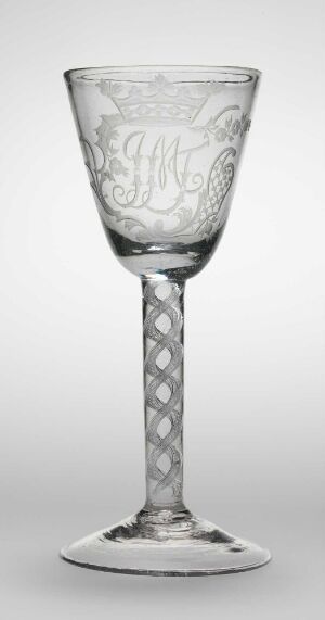  A clear glass goblet known as "Snekk kelchen," set against a light background, featuring an etched or engraved bowl design, a stem with a circular dotted pattern, and a stable, flat base. The glass exudes an aura of delicate craftsmanship and timeless design.