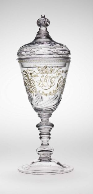  An intricate clear glass goblet with a lid, featuring a spherical finial, an etched decorative band around the bowl, a textured stem, and a stable flared base, set against a soft grey background.