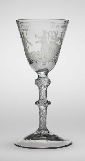  A black and white image of an intricately designed, engraved glass goblet from Nøstetangen glassverk, featuring a broad bowl, a decorative stem with bulbous elements, and a flat round base.