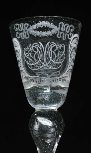  Engraved glass goblet titled "Perlkelchen" by Nøstetangen glassverk, displaying intricate symmetrical floral patterns on its transparent surface, set against a black background.