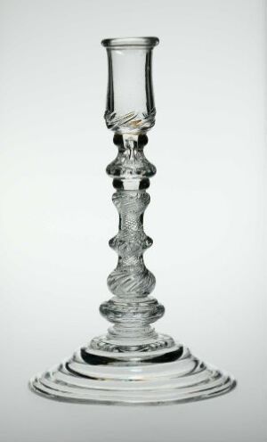  A transparent glass candlestick with intricate designs, set against a light background.