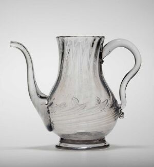  A clear glass pitcher with vertical fluting, a large handle, and a pouring spout, against a light gray background. Artist name and title are unknown.