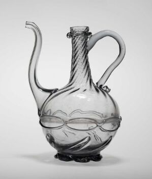  A transparent glass ewer with a bulbous body and elongated neck, featuring a wavy design around the central part and a gracefully arching handle on the side, set against a plain light background. Artistname and title are unknown.