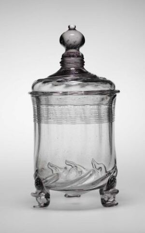  An antique-style transparent glass jar with a fitted lid, decorated with etched fish motifs, and supported by three glass feet. The jar and lid have a soft, clouded transparency which suggests an aged or vintage quality.