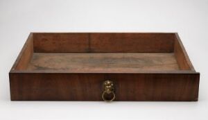  A wooden tray with warm brown tones and a natural grain showcasing an antique metal drawer pull on the front, set against a neutral backdrop. Artist name and title of the work are unknown.