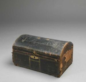  A weathered antique trunk with a curved top, dark brown in color with a patinated surface and tarnished gold-colored metal fittings, indicative of a bygone era of travel.