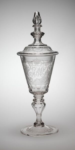  An engraved glass piece designed by Heinrich Gottlieb Köhler, featuring an elegant lid with a decorative finial, an urn-shaped body with intricate engravings, and a stem leading down to a stable foot, all presented in shades of gray against a gradient gray background.