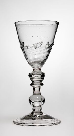 
 A clear glass goblet with floral engravings on the bowl and a decorative, spherical stem, set against a light grey background.