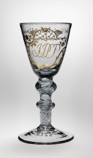  An elegant and ornate clear glass goblet with gold leaf and black decorations, featuring a monogram with intertwined letters "JPF" on the bowl, a twisted helix design on the stem, and a simple gold-edged base, against a neutral background.