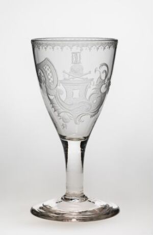  A clear glass goblet with intricate engravings on the bowl, featuring a long stem and circular base, standing against a white background.