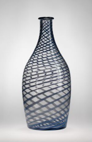  A tall, blue glass vase featuring a net-like dark pattern overlaying it sits against a plain, light background.