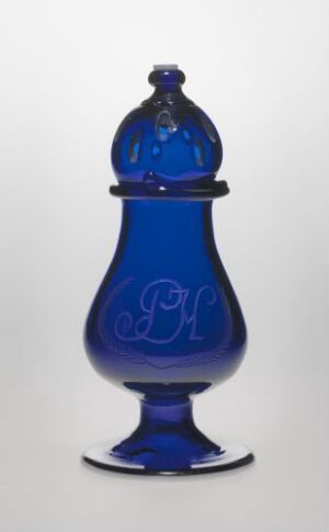  A blue glass jar with an intricate 'P H' monogram, featuring a matching lid, set against a light grey background, showcasing the beauty of cobalt blue glass craftsmanship.