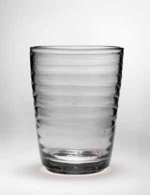  A clear glass tumbler with horizontal ridges sits on a plain background, exuding simplicity and functionality.