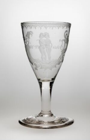  A transparent etched glass wine goblet with a romantic scene depicting two figures surrounded by foliage designs on a light-gray background with a subtle reflection underneath.