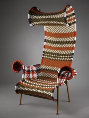  "Shadowy" armchair by Moroso, featuring a high-backed, throne-like design with an elaborate pattern of woven nylon threads in red, cream, black, and brown, finished with color-lacquered metal legs.