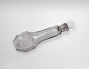  An elongated clear glass perfume bottle with a spherical stopper and multi-faceted body against a light grey background, showcasing sparkling reflections and a sophisticated design.