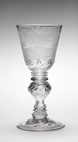  A Nøstetangen glassverk's clear engraved drinking glass on a gradient grey background. The elegant glass features a conical bowl atop a sculptural stem with a helical twist and a stable base. The piece exudes an air of antique craftsmanship and sophisticated design.