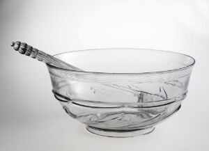  A clear glass bowl with a twisted handle glass mixing spoon inside, set against a soft white background.