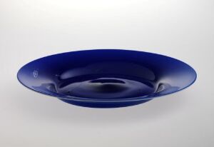  A deep blue, shallow, wide-rimmed bowl with a glossy finish, centered on a light to white gradient background.