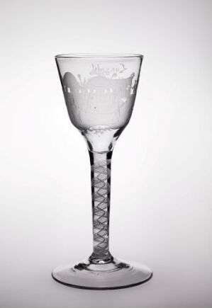  A clear glass goblet with an elegant design featuring a beaded spiral in the stem, against a light background with water droplets visible inside the bowl.