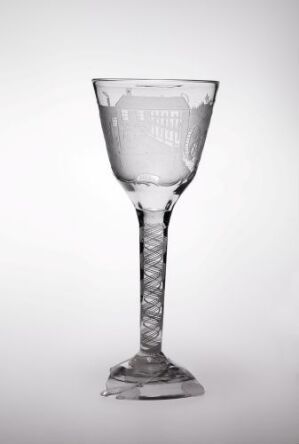  An elegant, clear glass wine goblet with a twisted stem stands against a light gray background, reflecting soft light and shadows on its polished surface.