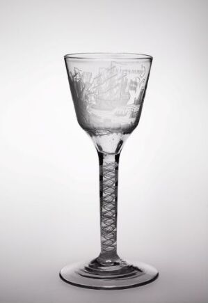  A clear glass wine goblet with an etched bowl and a spiral-twisted stem stands against a light grey background, showcasing elegance through its transparent and intricate design.