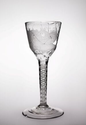  A clear glass goblet with a spiral stem is filled with a liquid that has been recently disturbed, causing a dynamic splash against the sides, set against a white or very light grey background.