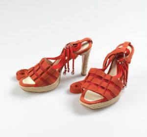  A pair of Helmut Lang Espandrie Plateau Sandals with rich red cotton straps in a crisscross pattern adorned with tassels, contrasting cream heels resembling natural cordage, and materials including metal, leather, and cotton, indicating a luxe and durable design.