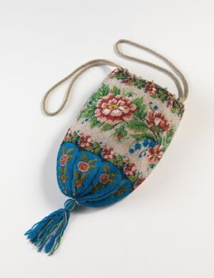  A vintage-style embroidered purse with a metal frame and handle, adorned with intricate floral patterns in blue, red, green, and yellow, featuring a decorative blue tassel at the bottom.