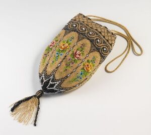  A vintage-inspired, teardrop-shaped evening bag with creamy beige fabric, a brown lace overlay at the top, hand-stitched colorful floral motifs, gold threading, iridescent sequins, and a thick gold tassel at the bottom, against a light background.