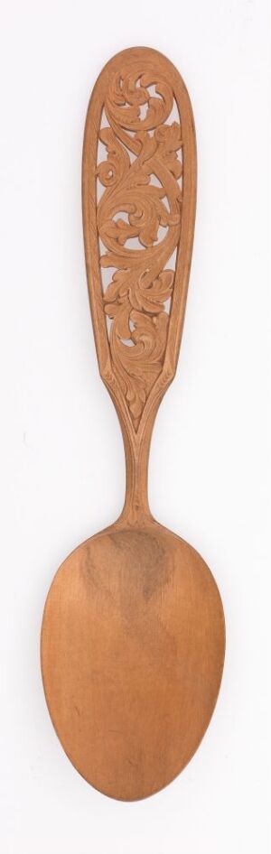  A slender wooden spoon with a series of decorative oval cutouts in the handle, displaying a warm brown color against a light beige background. Artist name and title are unknown.