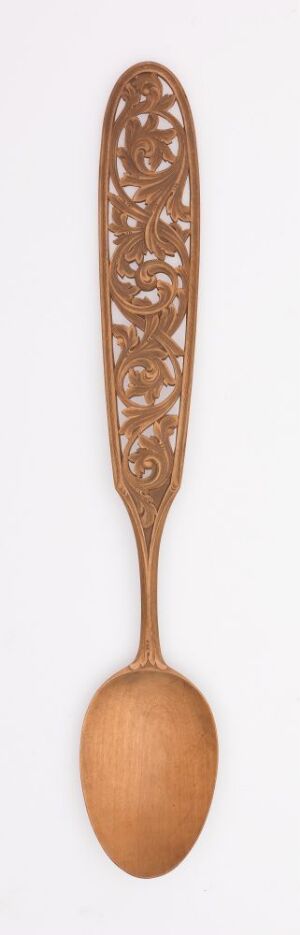  An elongate, ornately carved wooden spoon with intricate lace-like patterns on the handle, set against a light neutral background.