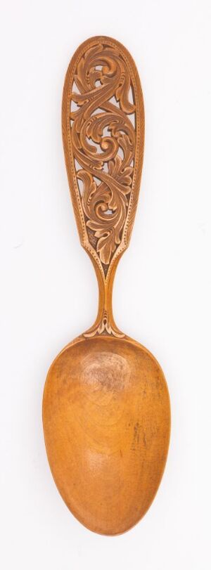  An antique wooden spoon with a decorative carved handle, displayed against a plain white background, showcasing the natural golden-brown tones of the wood.