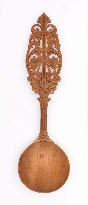  A decorative wooden spoon with an intricately carved handle featuring a symmetrical, lace-like openwork design, against a light background.